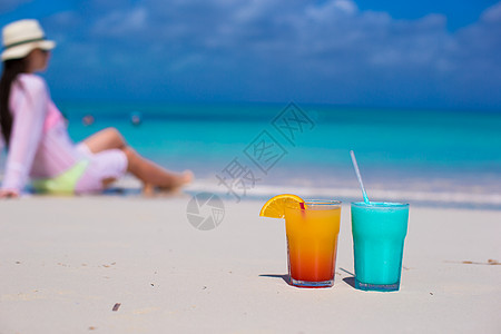 蓝Curacao和芒果鸡尾酒 在海滩背景的年轻女孩上图片