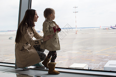 母亲和小女儿在机场候机楼窗外看望着窗户 航空图片