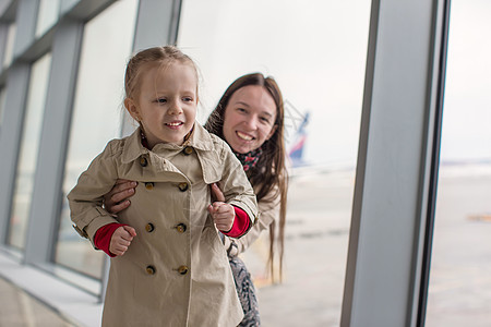母亲和小女儿靠近机场候机楼窗户的窗口图片