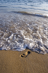 在海沙沙滩和海浪上单脚踏足图片