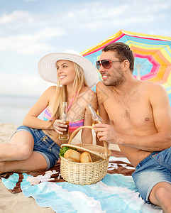 在海滩上野餐的一对笑着微笑的情侣 伞 非酒精性图片