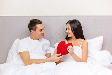 双在床上微笑的情侣与红心型枕头 浪漫 浪漫的 庆典图片