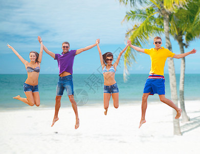 一群朋友或夫妇在海滩上跳跃 自由 自由的 庆祝 女孩们图片