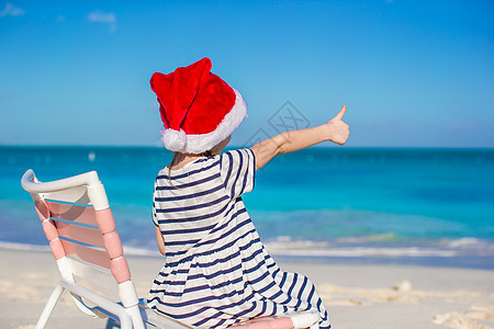 穿红色圣诞礼帽的可爱小女孩 在沙滩椅上 热带图片