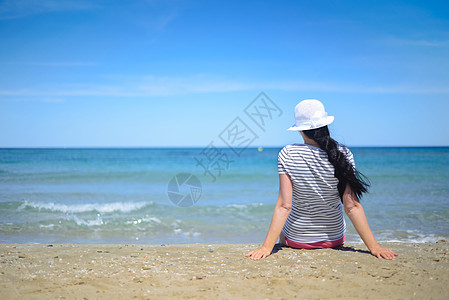 年轻女人坐在沙沙上 望着大海图片