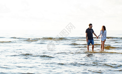 海滩上漂亮的一对夫妇 晚上 衬衫 手 水 波浪图片