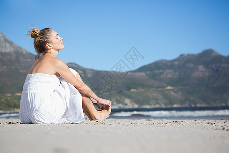 坐在沙滩上穿着白裙子的金发美女 女性 海滩 闭着眼睛图片