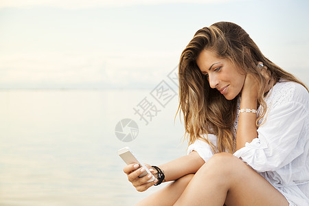 使用手机微笑美丽的年轻女性的美丽女士高清图片