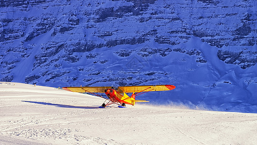 黄机降落在瑞士冬季山雪滑雪场上图片