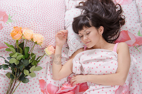 在睡觉的年轻女孩旁边的床上放花图片
