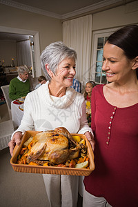 妇女当着家人的面冒火烤火鸡 老年 祖母 快乐的 桌子图片
