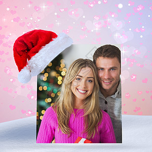 幸福情侣相互拥抱的复合形象 雪花 下雪 房子 圣诞帽图片