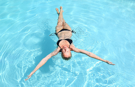美丽的高加索女士漂浮在游泳池里图片