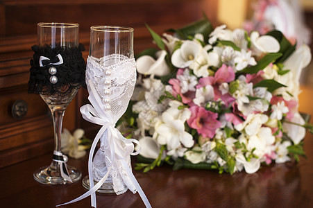 两杯结婚眼镜和两束婚礼花 放在夏季花园的石头上图片