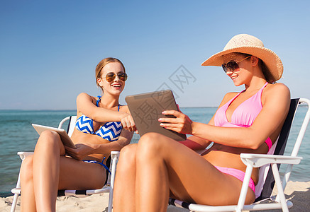 海滩上手持平板电脑的微笑着妇女 快乐的 假期图片