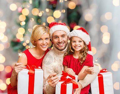 带着礼物盒的圣塔帮手帽子中的幸福家庭 快乐图片