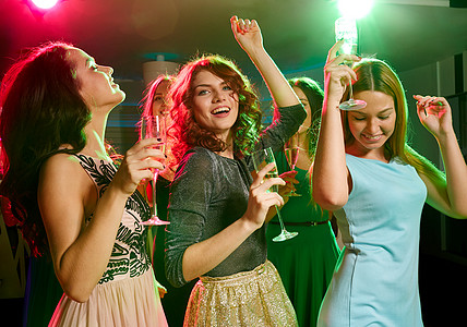 递水杯女孩俱乐部里带着香槟杯的笑着朋友 夜店 出去 喝背景