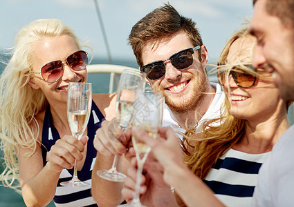 在游艇上带着香槟杯的笑着朋友 男人 朋友们 太阳镜图片