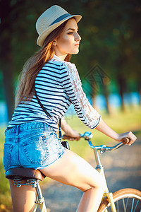 戴着帽子的可爱年轻女子在户外骑自行车 迷人的图片