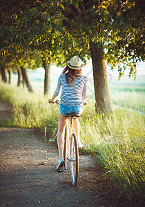 戴着帽子的可爱年轻女子在户外骑自行车 女士图片