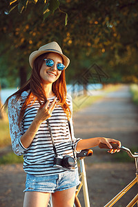 戴着帽子的可爱年轻女子在户外骑自行车 路图片