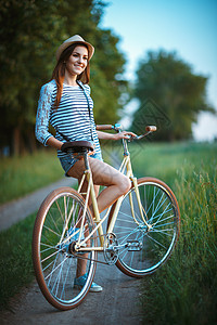 穿着帽子和户外自行车的可爱年轻美女 裙子 自然图片