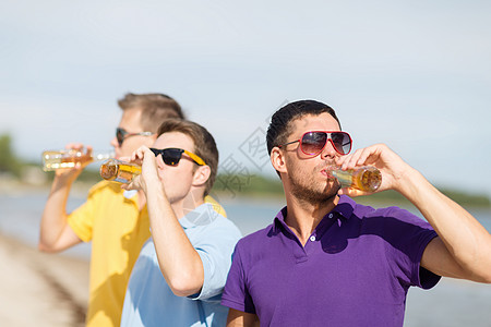 快乐的朋友在海滩上喝啤酒瓶 青少年 放松 男性图片