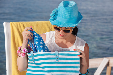 美丽的女人在沙滩上看着她的包包 自然 休息 海图片