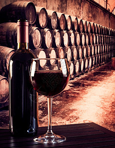 在旧酒窖背景的瓶子附近的红葡萄酒杯图片