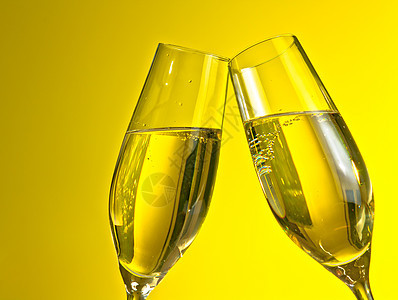 一对带有黄光背景金泡泡的香槟长笛子图片
