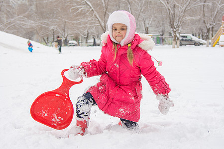 女孩从雪雪上爬起 与雪橇一起漂浮在一起图片