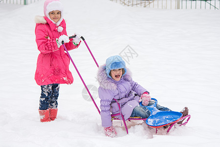 两个女孩骑着雪橇 互相搭乘图片