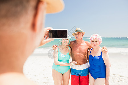 高年男子拍朋友相照 蓝色的 微笑 手机 阳光 游泳衣图片