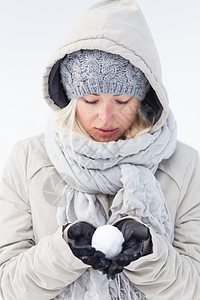 女孩在寒冷的冬天拿着雪球 霜 帽 抓住图片