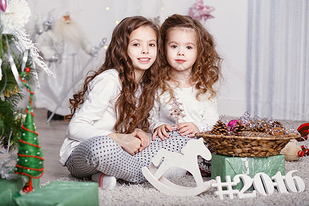 两个小女孩穿着舒适的家服 坐在瓶子上坐着图片