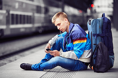 年轻旅行者 铁路 年轻的 耳机 平台 行李 游客 无线技术 背包背景图片
