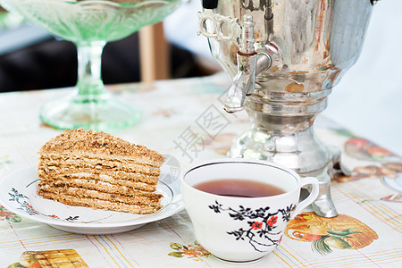 一个盘子上一块蛋糕的蜂蜜蛋糕 一杯茶和一杯萨莫瓦 复古的 早餐图片