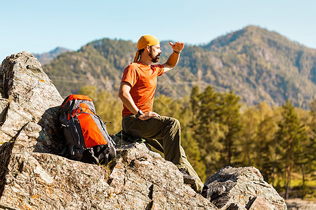 留着胡须的年轻男性正在穿越山区 旅游背包站在岩石山上 同时欣赏自然景观 在山区度过暑假 背包旅行 假期图片
