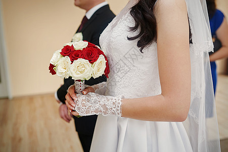 新娘在仪式上举着白色和红玫瑰花束图片