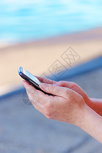 女性用手在海边的移动电话上发短信 无法识别的智能手机图片