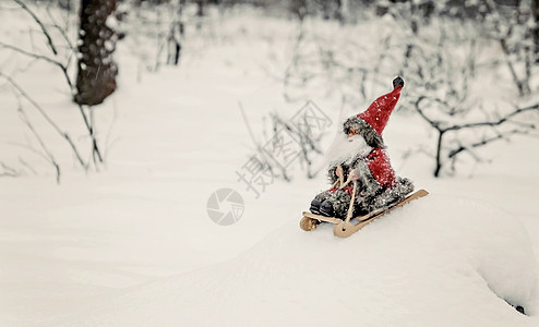 玩具圣诞老人在白雪皑皑的森林里的雪橇上 礼物图片