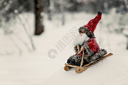 玩具圣诞老人在白雪皑皑的森林里的雪橇上 滑动图片