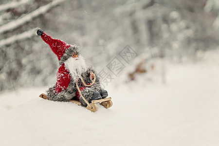 玩具圣诞老人在白雪皑皑的森林里的雪橇上 展示图片
