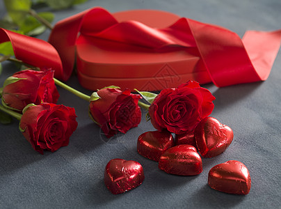 红玫瑰和光碟形状盒前的红红心巧克力图片