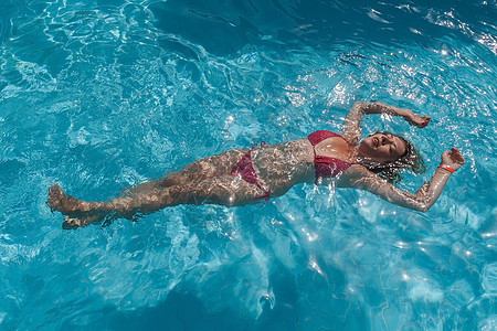 美丽的女人在游泳池里漂浮图片