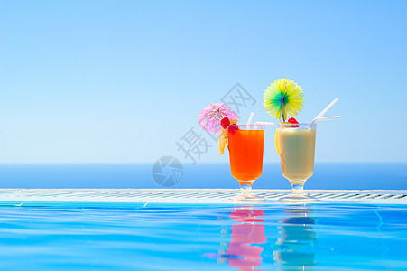 在温暖蓝海背景游泳池附近的两家多彩热带鸡尾酒馆 夏季绝食节日 橙子 水池图片