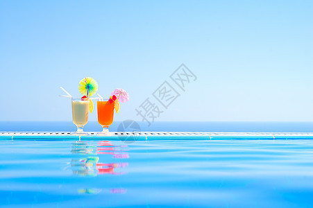 在温暖蓝海背景游泳池附近的两家多彩热带鸡尾酒馆 夏季绝食节日 水果 奢华图片