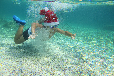 圣诞老人帽子男孩在海上游泳 孩子 享受 绿松石 童年图片