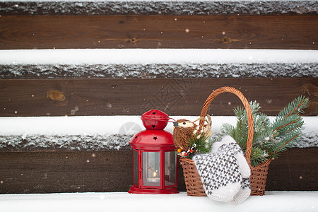 在雪地楼梯上红灯笼附近的篮子里装有圣诞树玩具和羊毛手套图片
