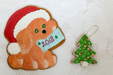 两个姜饼饼干形状为圣诞树和白色餐巾背景上的狗 顶视图 平躺 复制空间 卷曲的圣诞姜饼家常菜 2018 年新年快乐图片